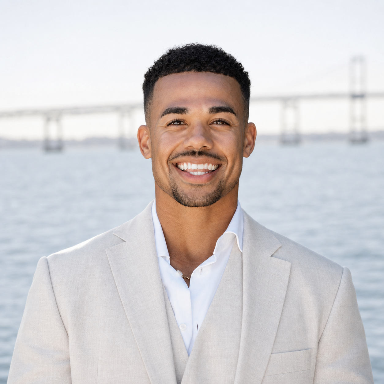 Garrett Jones in a light suit before a softly blurred waterfront bridge